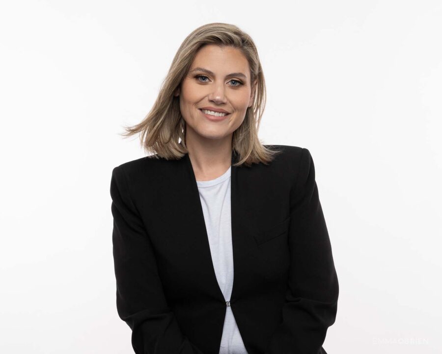 woman in a black jacket photographed against a white studio backdrop