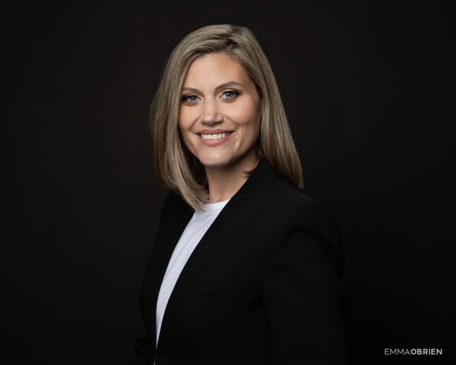 woman in a black jacket photographed against a black backdrop