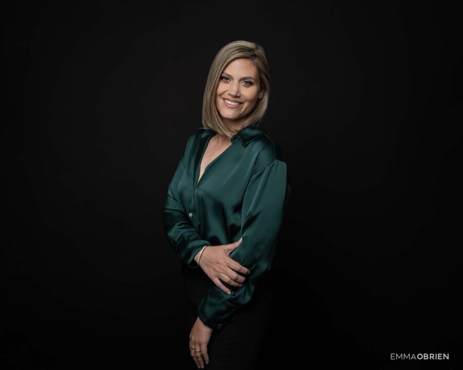woman in a green blouse photographed against a black backdrop