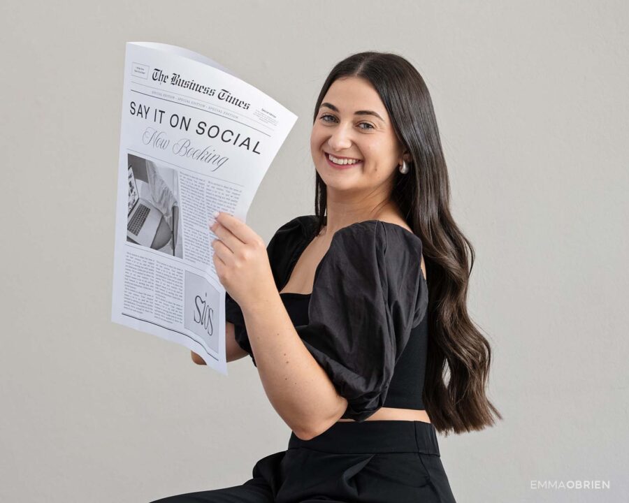 woman smiling behind a newspaper