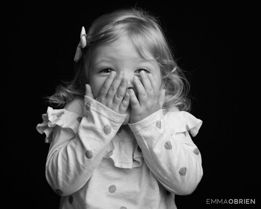 Little girl laughing and holding her hands over her face