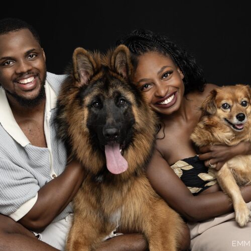 Couple and their dogs photographed in studio against a black background